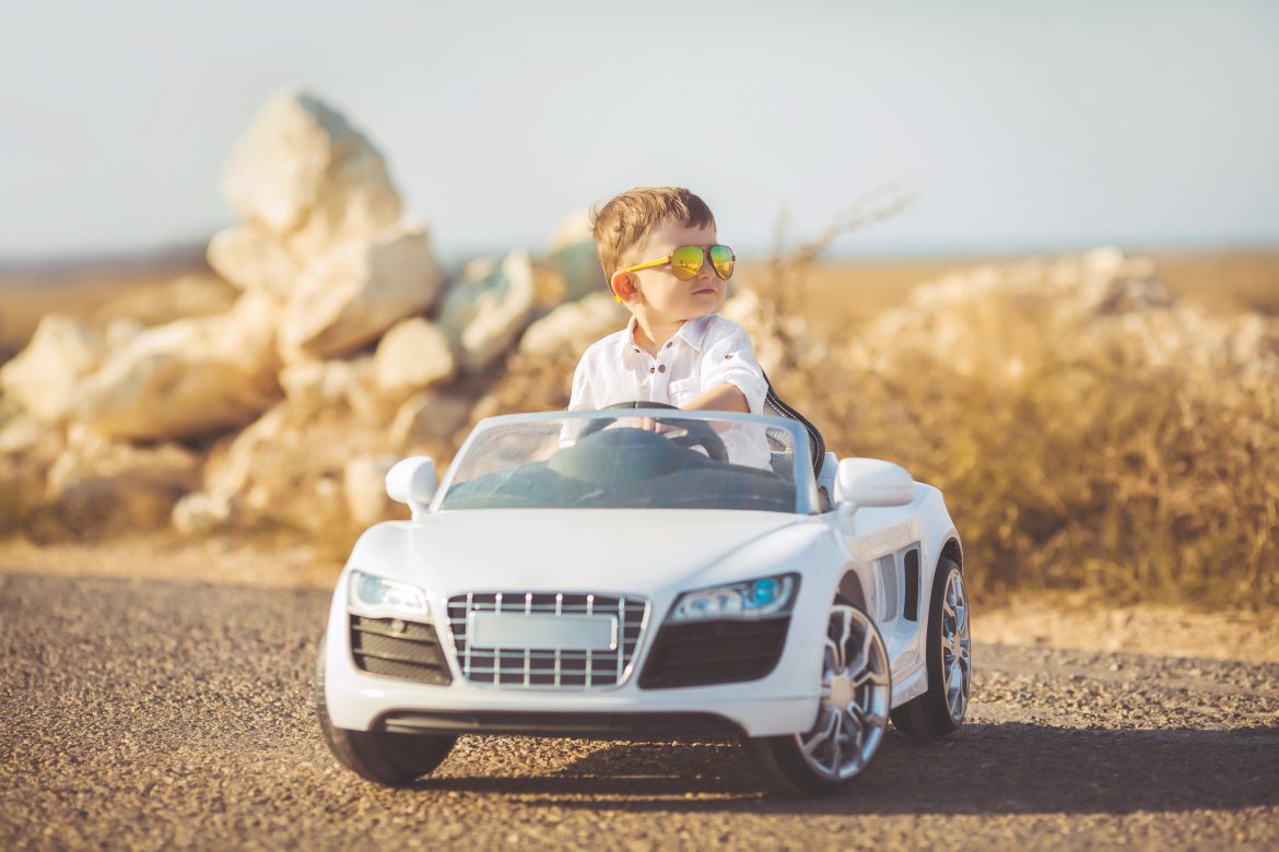 Happy little boy travel by car in summer Top 10 Best Ride On Cars For Kids