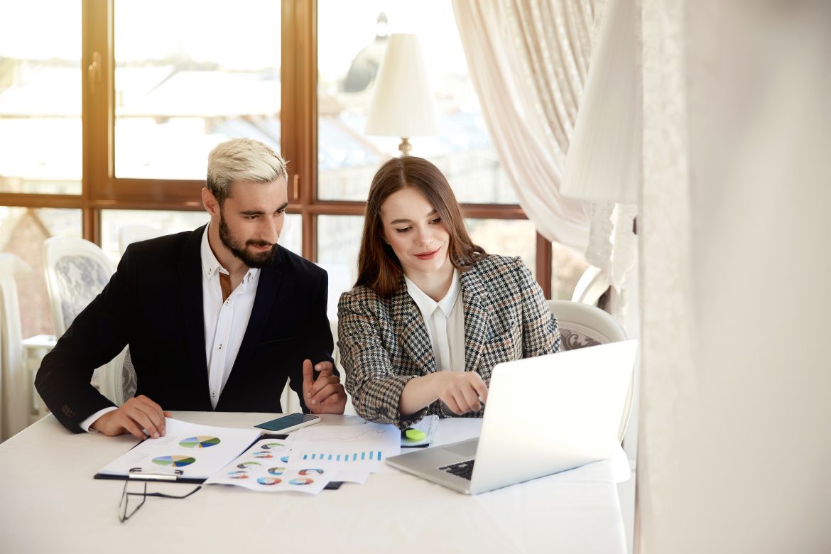 Young blonde man and brunette woman are looking at the computer Investment Management Services: How Financial Advisors Can Enhance Your Portfolio